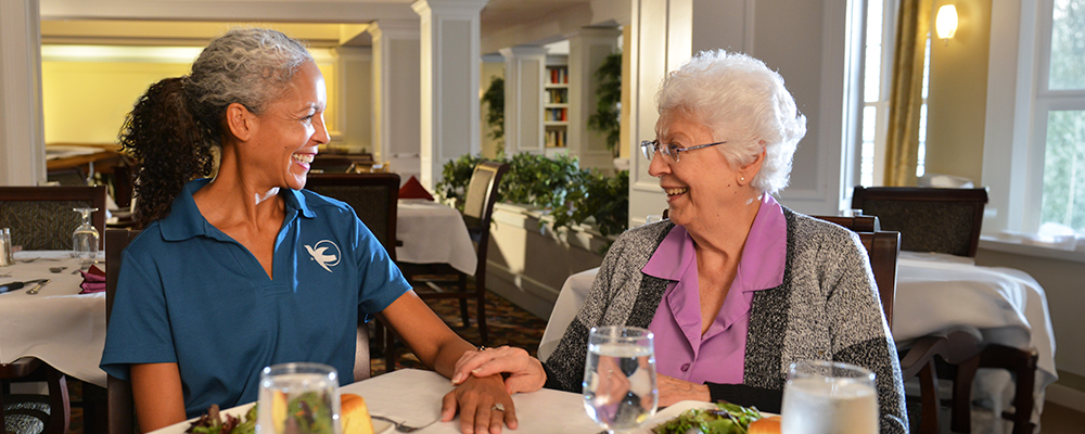 A Visiting Angels caregiver comforting an elderly woman with Alzheimer's, highlighting compassionate support in a peaceful home setting.