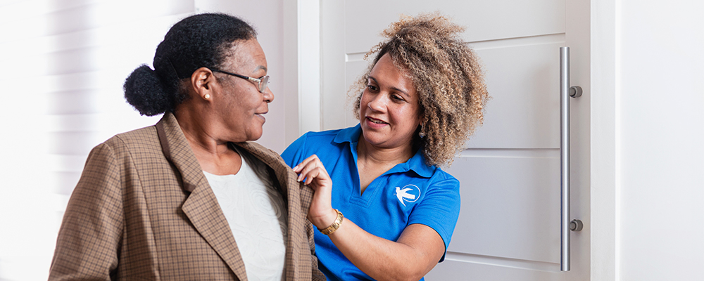 A Visiting Angels caregiver comforting an elderly woman with Alzheimer's, highlighting compassionate support in a peaceful home setting.