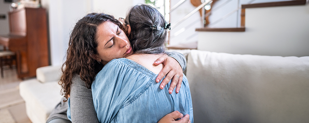 A Visiting Angels caregiver comforting an elderly woman with Alzheimer's, highlighting compassionate support in a peaceful home setting.