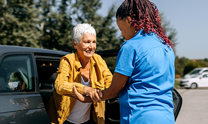 A Visiting Angels caregiver helping an elderly patient transition from a hospital bed to a home setting, illustrating support during recovery.