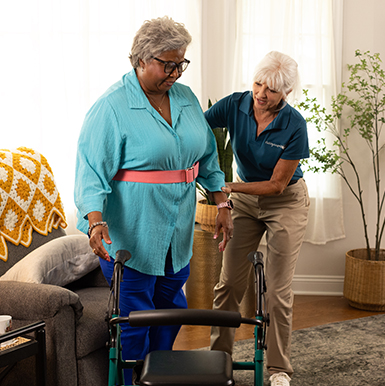 A Visiting Angels caregiver demonstrating proper techniques for using mobility aids with an elderly man, emphasizing fall prevention in a home setting.