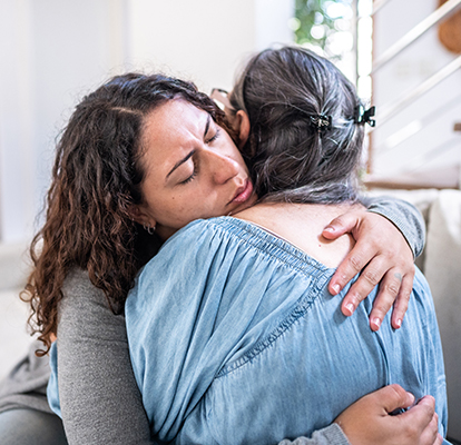 A Visiting Angels caregiver comforting an elderly woman with Alzheimer's, highlighting compassionate support in a peaceful home setting.